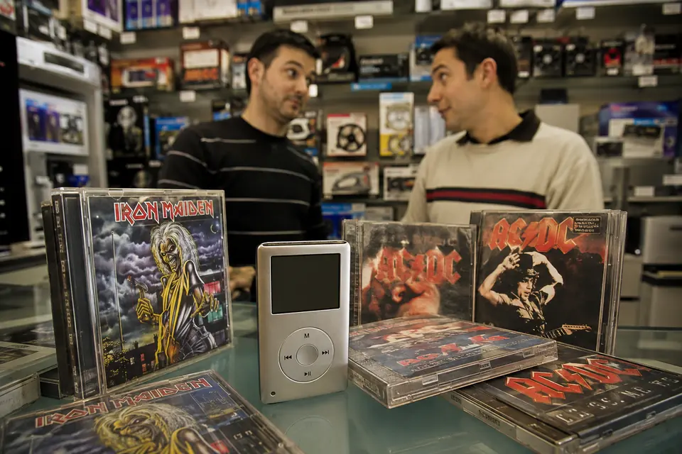Reproductor MP4 rodeado de discos de AC/DC e Iron Maiden en una tienda de informática