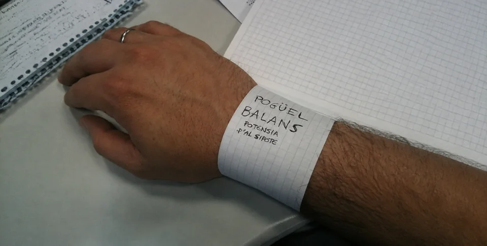 Pulsera de papel cuadriculado que parodia Power Balance, sobre una muñeca junto a un cuaderno