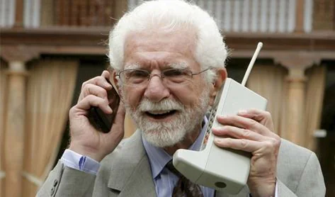 Martin Cooper sosteniendo dos teléfonos móviles de distintas generaciones