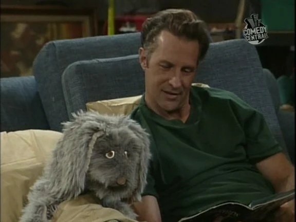 Jack Malloy sentado en el sofá junto al conejo Mr. Floppy