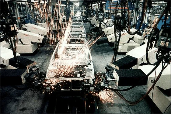Robots industriales en una fábrica de automóviles Robots industriales soldando una carrocería en una fábrica de automóviles