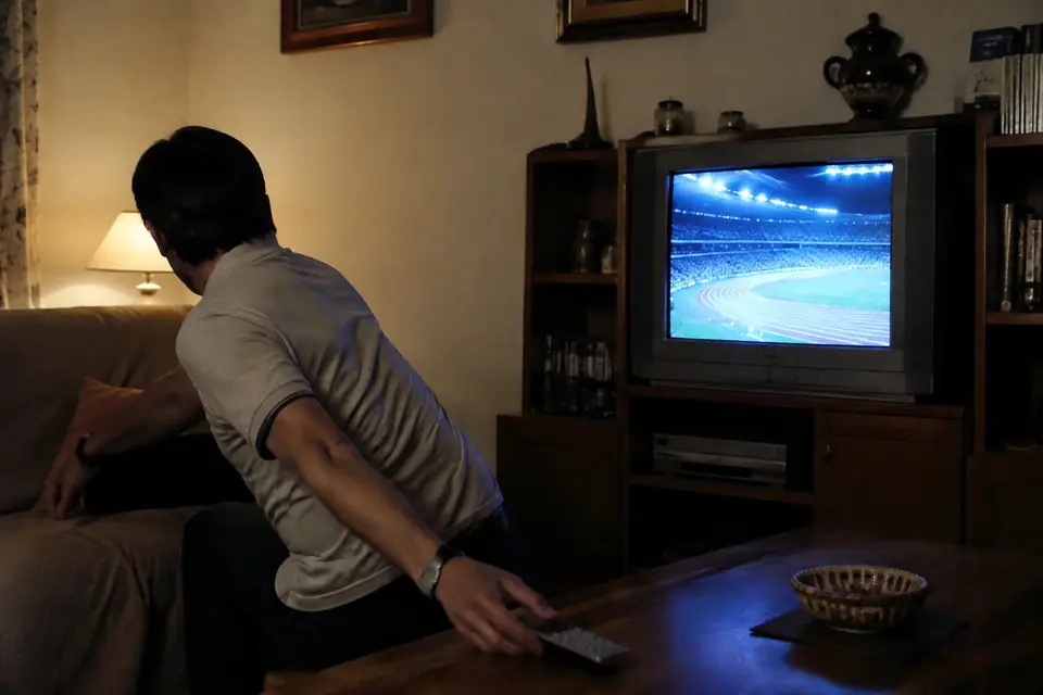 Espectador apartándose de un televisor que emite atletismo